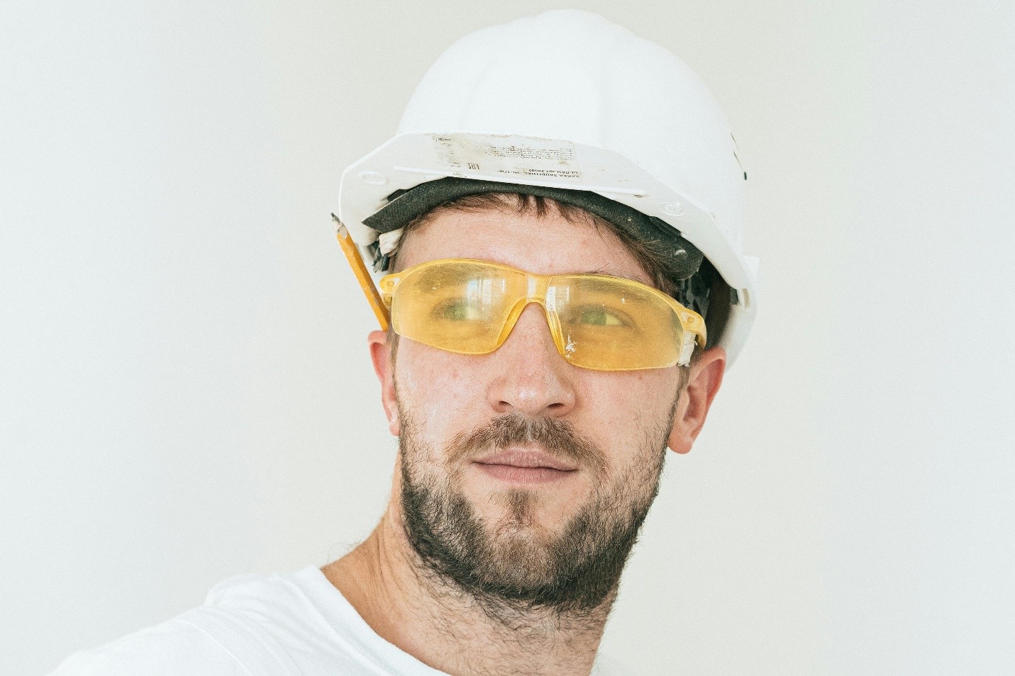 Construction Safety Officer wearing a hard hat and safety glasses, looking focused and alert on-site, ensuring workplace safety compliance.